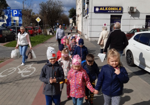 Dzieci poprawnie idą częścią chodnika przeznaczoną dla pieszych obok ścieżki rowerowej.