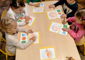 Wykonanie karty pracy dziecko koloruje kontury dyni.