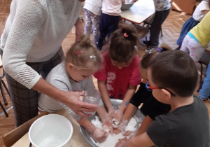 Dzieci tworzą z mąki ziemniaczanej i wody ciecz nienewtonowską , zabawa sensoryczna.