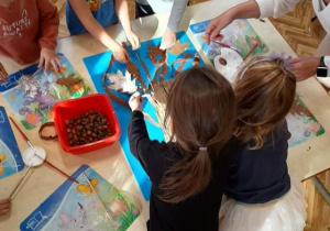 Dzieci wykonują drzewa z wykorzystaniem materiału przyrodniczego.