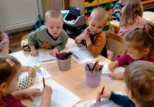 Dzieci kolorują rysunek doniczki.