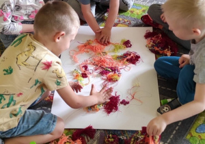 Dzieci wykonują pracę plastyczna z włóczka.