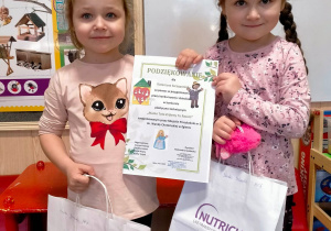 dwie dziewczynki pokazują dyplom i prezenty