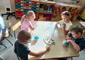Dzieci siedzą przy stole i malują