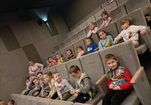 Dzieci siedza na fotelach w kinie