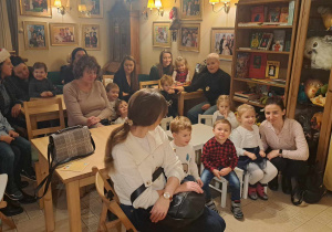 Dzieci i rodzice siedzą na krzesłach