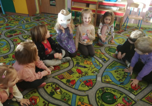 Dzieci siedzą na dywanie w maskach