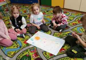 Dzieci siedzą na dywanie i pozujado zdjęcia