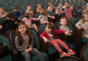 Dzieci siedzą na fotelach w teatrze