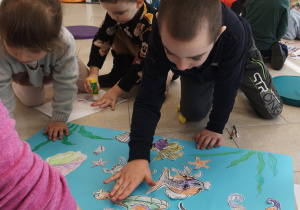 Dzieci przyklejają morskie stworzenia na plakacie