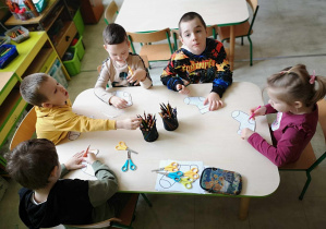Dzieci kolorujaskarpetki przy stolikach