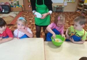 Dzieci z pomocą prowadzacej przygotowuja ciasto na pierogi.